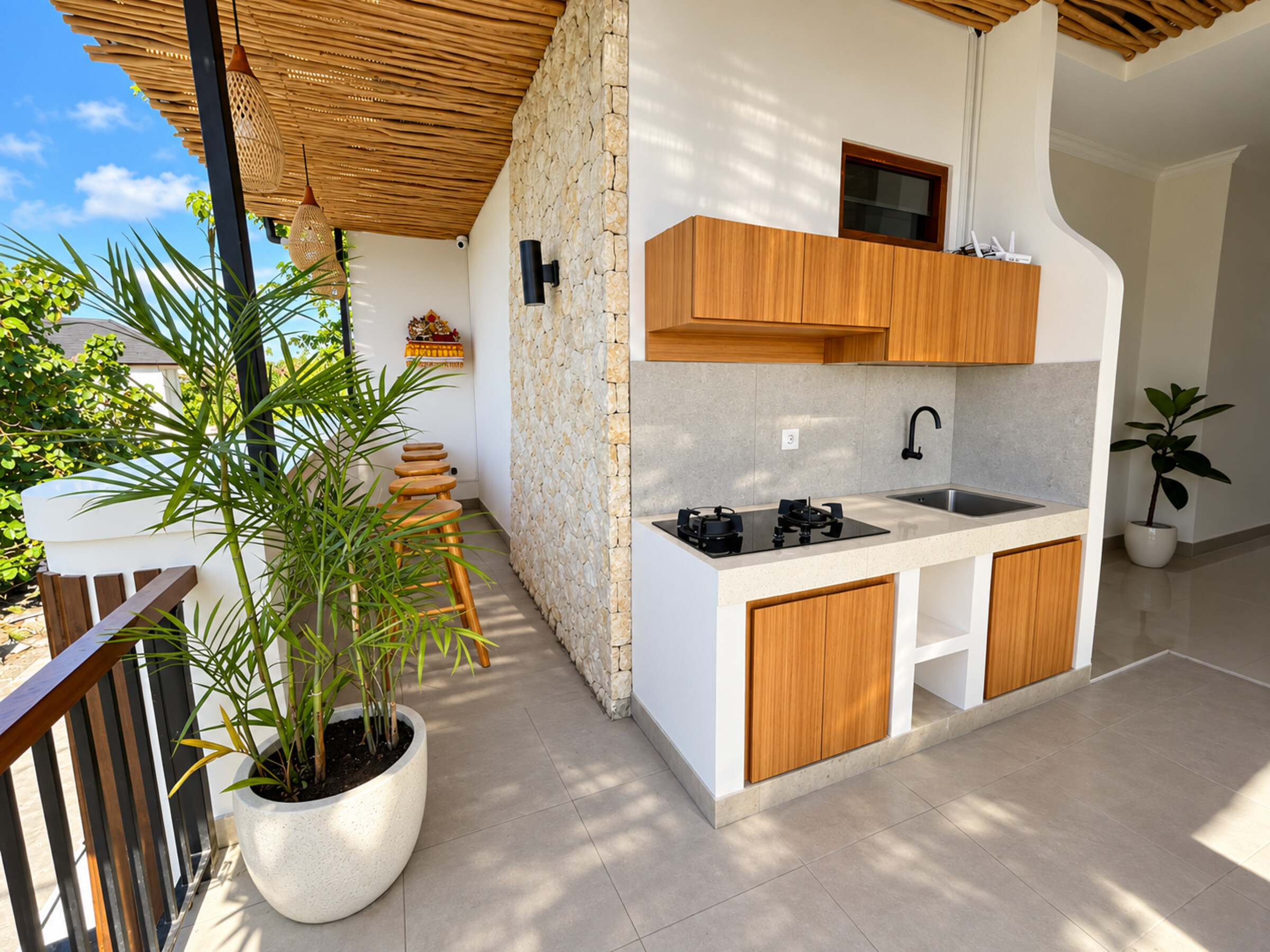 Balcony kitchenette with a two-burner stove, sink and wooden cabinets